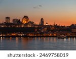 The Quebec City skyline and its illuminated buildings seen at dusk from Lévis, with the St. Lawrence River in the foreground