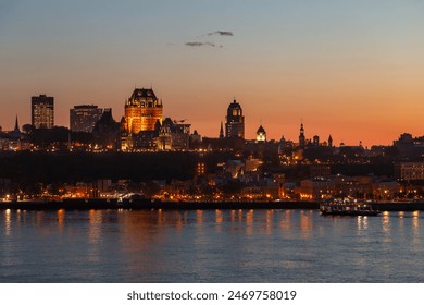 The Quebec City skyline and its illuminated buildings seen at dusk from Lévis, with the St. Lawrence River in the foreground - Powered by Shutterstock