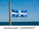 Quebec Provincial flag on wooden pole overlooking Saint Lawrence seaway.