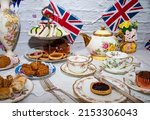 Queen Elizabeth II Platinum Jubilee cream tea street party food red white and blue flags  with celebration Union jack food toppers on a white vintage table cloth with Union jack flags