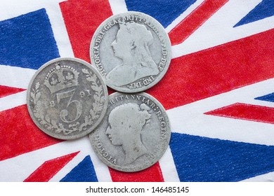 Queen Victoria Three Silver Threepences From The 19th Century (from 1873, 1891, 1898) On A British Flag. The Coins Have Been In Circulation. Concept For History Of British Empire Or Collecting Coins.