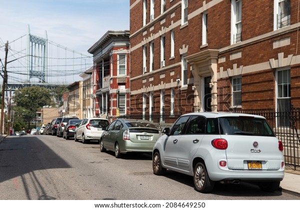 Queens, New York USA - August 7\
2021: Row of Parked Cars on a Street in Astoria Queens New York\
with Residential Buildings and a view of the Triborough Bridge \
