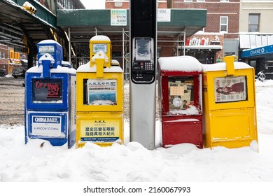 Queens, New York USA - January 29 2022: Multi Language Newspaper Boxes Covered In Snow Along A Sidewalk In Astoria Queens New York During The Winter