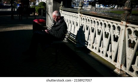 QUEENS TOWN, NEW ZEALAND - May 06, 2017: An Old Man Sitting On A Chair In A Park In Queens Town, New Zealand