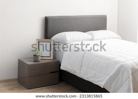 A queen-sized bed in a room featuring a wooden floor and white bedding