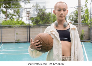 Queer non-binary Asian model holding basketball outdoors