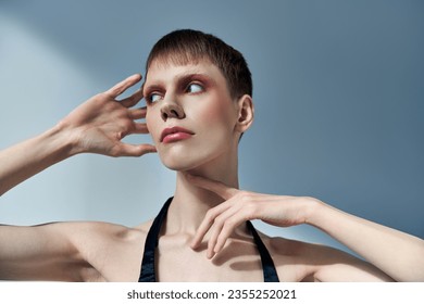 queer person with makeup looking away and posing on grey backdrop, beauty, visage, androgynous - Powered by Shutterstock