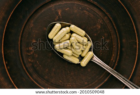 quercetin capsules on a spoon on a clay plate. mental wellbeing and personal health concept