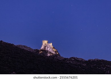 Queribus castle under the stars at night,  rocky hilltop on summer night, Cucugnan, Cathar Country, Corbieres mountains, Occitanie, France - Powered by Shutterstock