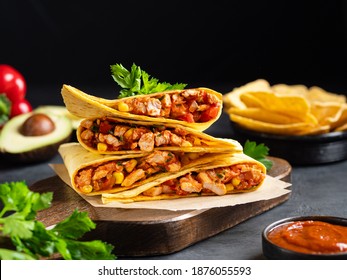 Quesadillas With Chicken Breast, Corn, Red Pepper, Tomatoes And Sauce Stacked On Wooden Cutting Board. Traditional Toasted Sandwich, Mexican Snack, Corn Tortilla Wraps And Nachos. Black Background.