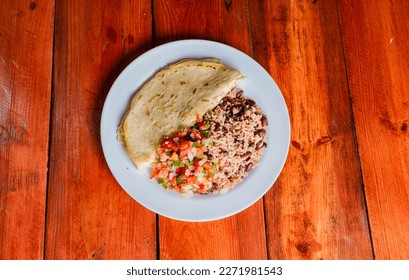 Quesillo dish with gallo pinto and pico de gallo on wooden table. Nicaraguan food Gallo pinto with pico de gallo and Quesillo served