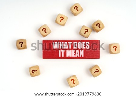 Question concept. On the table are cubes with questions and a red plaque with the inscription - What Does It Mean