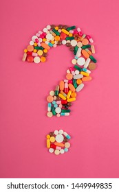 Question mark arranged from assorted pharmaceutical medicine pills, tablets and capsules on pink background