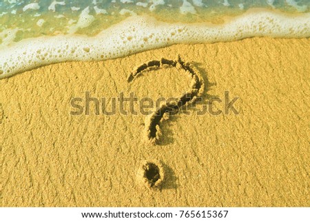 Question mark drawn in the sand on the seashore
