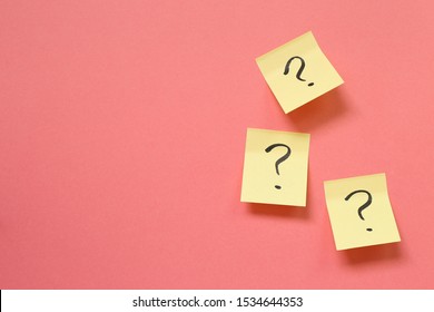 Question mark on memo paper on pink background. Solution concept