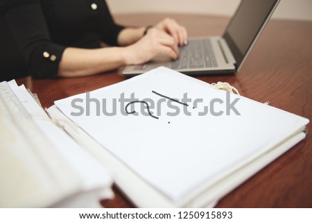 Question mark on paper documents. Deferred folder with working documents in the office. Legal assistance. Unsolved problem. Businesswoman working at the computer in the background.