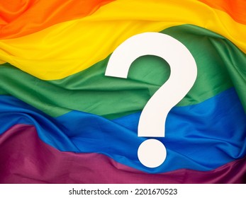 Question Mark Over The Rainbow Flag Or LGBT Flag Background. Top View. Close-up Photo