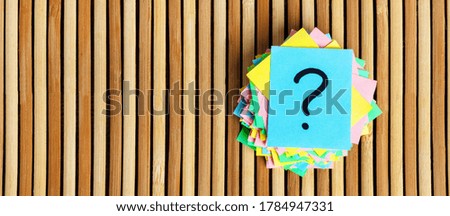 Question mark paper heap on table concept for confusion.
