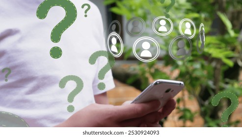 Question mark and profile icons floating against caucasian boy using smartphone in the garden. global networking and technology concept