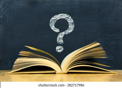 Question Mark Symbol Above Vintage Old Book On Blackboard Background