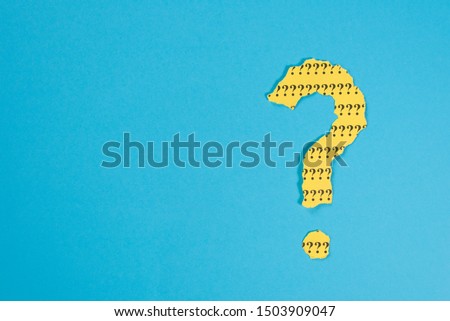 question mark symbol from a teared yellow paper on a blue background with copy space. Concept of FAQ, Q and A, Questions and riddle