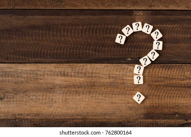 question mark tiles arranged forming bigger question mark. question mark on wooden table background