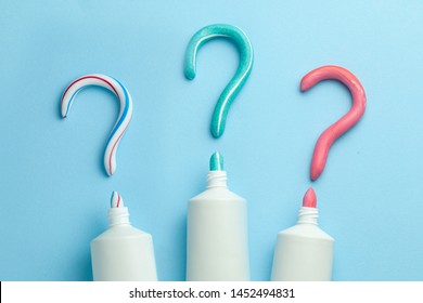 Question mark from toothpaste. Concept of choosing good toothpaste for teeth whitening. Tube of colored toothpaste on blue background. Copy space for text