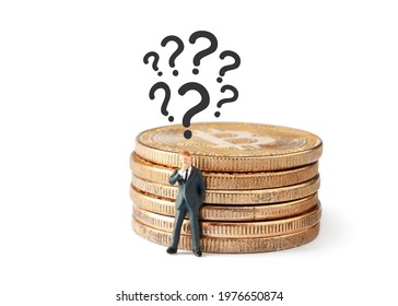 Question marks above thinking businessman figurine while leaning to shiny bitcoin stack on white background.. Developing a business strategy.  Cryptocurrency, blockchain or trading concept.