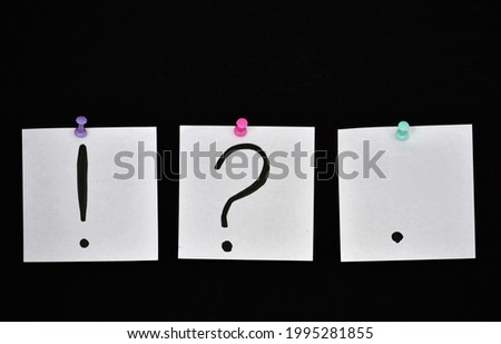 question marks exclamation point and dot on bloy note on black background 