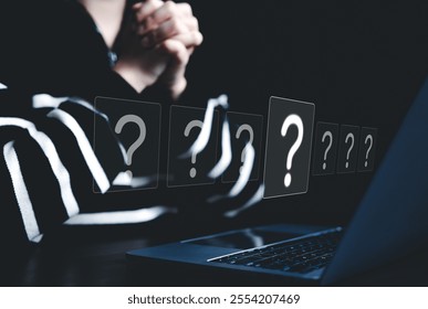 Question Marks and Problem Solving Concept. A person sits in front of laptop, surrounded by floating question mark icons, symbolizing inquiry, decision-making, and problem-solving in digital context.