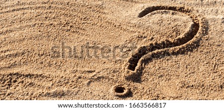 question marks written on beach sand close up, with copy space.