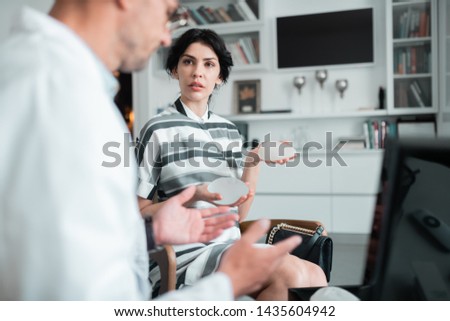Questions about implants. Dark-haired client of plastic surgeon asking questions about implants