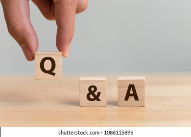 Questions and answers concept. Hand putting wood block cube with alphabet Q&A on wooden table
