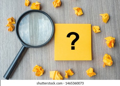Questions Mark ( ? ) word on yellow note with crumbled paper and magnifying glass on table background. Idea, Analysis, Keyword, Content, SEO,FAQ, Answer, Q&A and Information concept