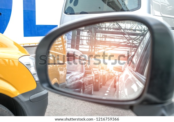 queue at the border for customs control, all at the\
terminal of the car to enter or exit the ferry boat, reflected in a\
mirror side view