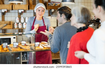 Queue of customers is lined up at counter of bakery. People place order at bakery, buy sweet pastries in cafeteria, girl worker serving people