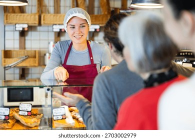 Queue of customers is lined up at counter of bakery. People place order at bakery, buy sweet pastries in cafeteria, girl worker serving people