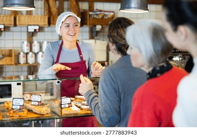 Queue of customers is lined up at counter of bakery. People place order at bakery, buy sweet pastries in cafeteria, girl worker serving people