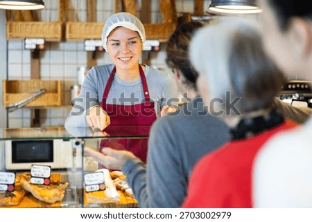 Queue of customers is lined up at counter of bakery. People place order at bakery, buy sweet pastries in cafeteria, girl worker serving people