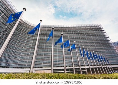 The Queue Of Steeples With Blue Flags Of The European Union Against The Background Of The European Commission Building In Brussels, Belgium. EU Flag, Symbol