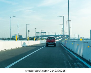 Quezon City, Metro Manila, Philippines - April 2022: A red pickup truck drives on the northbound lane of Skyway during the early morning.