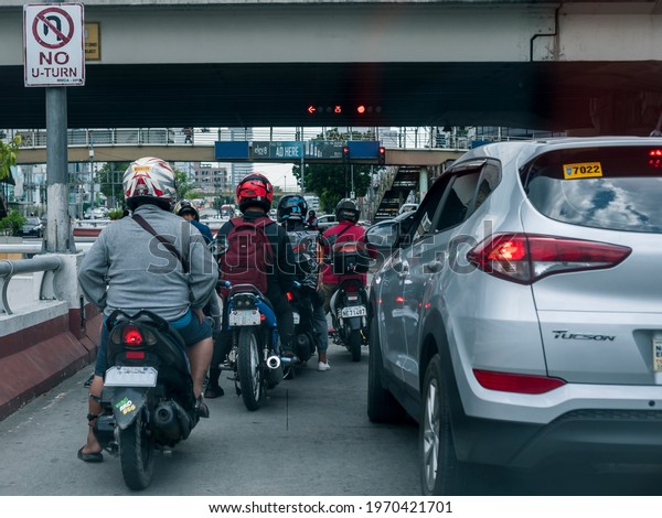 Quezon City, Philippines - Aug 2020: Motorbikes and\
a SUV wait for the traffic light to go green. At an intersection in\
Quezon Ave.