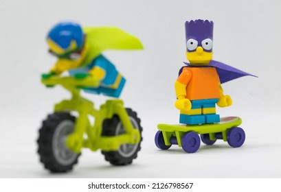 Quezon City, Philippines - February 20, 2022: Lego Simpson Minifigure Bart Simpson Bartman riding a skateboard behind Milhouse as Fallout Boy riding a motor bike