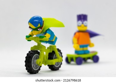 Quezon City, Philippines - February 20, 2022: Lego Simpsons Minifigure Milhouse as Fallout Boy riding a motorbike with Bart Simpson Bartman in the background