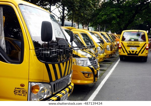 QUEZON CITY, PHILIPPINES - SEPTEMBER 6, 2016:\
School service vehicles line up and wait to fetch students at a\
parking lot of a school