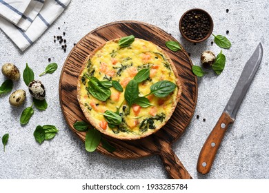 Quiche with salmon and spinach, cheese on a light concrete background. View from above.