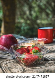 Quick Lunch In The Middle Of Nature On A Wooden Table.Strawberries, Apple, Meat Pie, Plastic Containers.One Cup.Take Away Food,outdoor Life.Copy Space