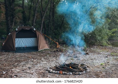 Quickly Folding Tent. It Stands On The Banks Of The River In The Forest. Wild Conditions. Camping And Hiking. Smokes A Fire. No People. Place To Insert Text.