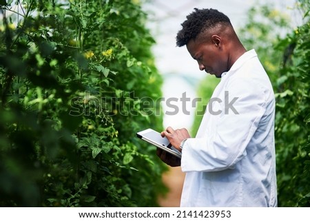 Quickly getting more info about this plant online. Shot of a handsome young botanist using a digital tablet while working outdoors in nature.