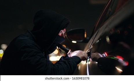 Quickly robber checking breaking entering alarm shines a flashlight in a car sitting stealing crime male thief illegal theft stolen danger burglary bandit secure safety money insurance door